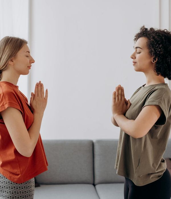 Woman in a calm yoga pose in a room with soft, natural lighting.